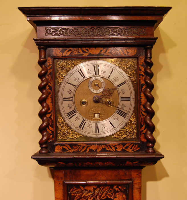 A fine William and Mary walnut and marquetry longcase clock by Charles Tolley of London , who was born in 1663 and survived the Great fire!. He was free of the Clockmakers Company in 1683 . The case is veneered in walnut with panels of bird and floral marquetry against an ebony ground.  There is an round brass lenticle to the trunk door and the hood ( ex rising) is flanked by Barley twist columns