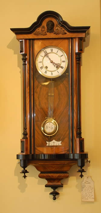 A German 'Vienna' wall clock in well figured Walnut and Beech case, with a Two piece enamel dial, and beautiful Blued steel Hands. Striking the hours and Half Hours on a Gong, it has wooden rod pendulum with a Brass Bob